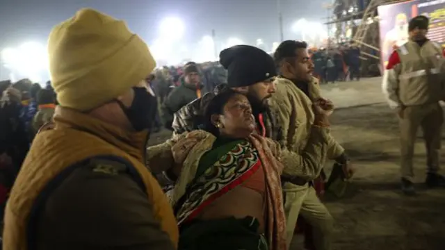 Police personnel carry a lady as she fainted at the site