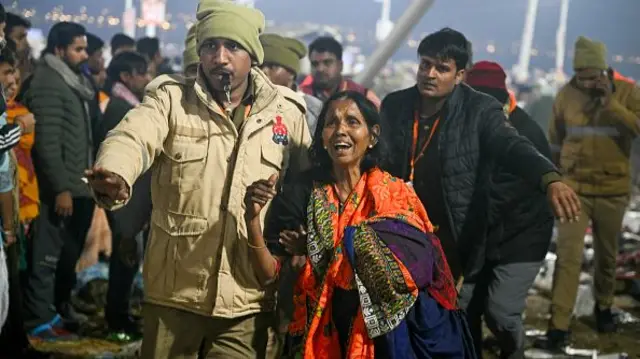 A devotee wearing a saree and her hair open being escorted by a policemen as she weeps at the site of stampede amid the ongoing Maha Kumbh Mela festival in Prayagraj on January 29, 2025