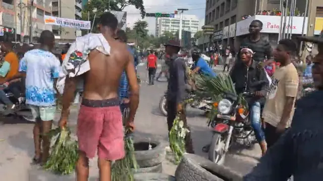 Protesters in Kinshasa pile care tyres on the road and ride motorbikes.