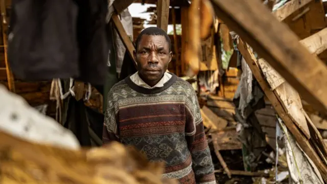 A resident stands in the remains of his house