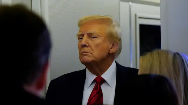 U.S. President Donald Trump looks on as he speaks to reporters aboard Air Force One