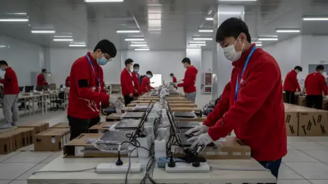 Tech workers in a factory in China, working on computers