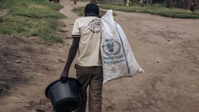 A man carries a bucket and a World Food Program (WFP) bag in a street of Kishishe, eastern Democratic Republic of Congo, in 2023.