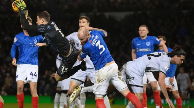 Millwall goalkeeper Liam Roberts claims a catch and clatters Portsmouth's Connor Ogilvie in the process