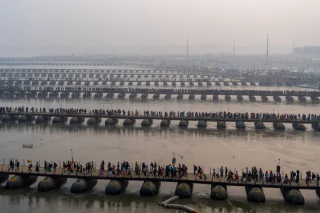 Hindu pilgrims walk over floating pontoon bridges to reach Sangam, the confluence of rivers Ganga, Yamuna, and mythical Saraswati on the occasion of Paush Purnima during the Maha Kumbh Mela festival in Prayagraj, Uttar Pradesh, India on January 13, 2025 (Photo by Amarjeet Kumar Singh/Anadolu via Getty Images)