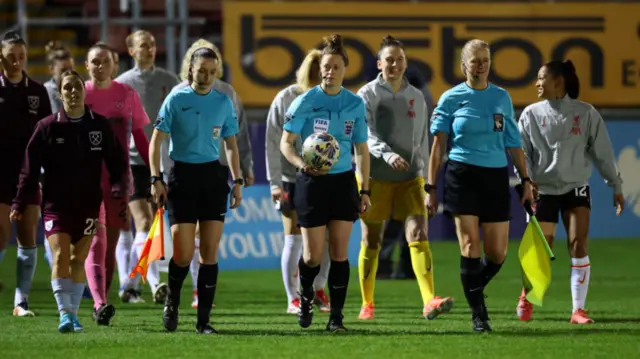 Match Referee Kirsty Dowle leads players and officials onto the pitch prior to The Adobe Women's FA Cup Fourth Round match between West Ham United and Liverpool