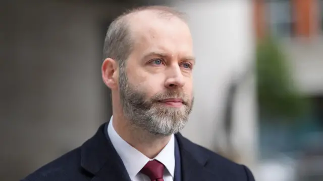 Jonathan Reynolds in a suit with blurred background