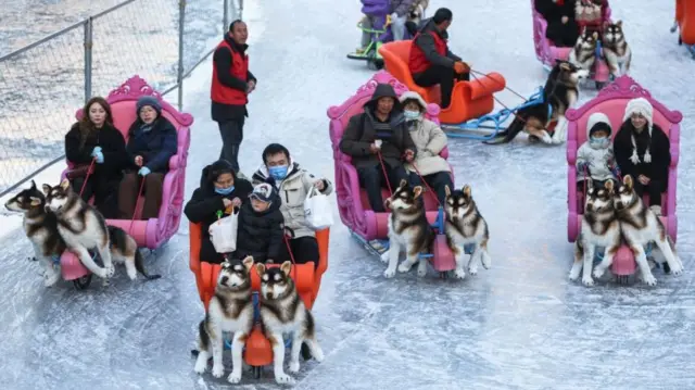 People skate in carts on a frozen lake in Beijing