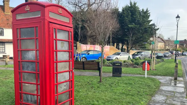 A red telephone box is seen on a front lawn.