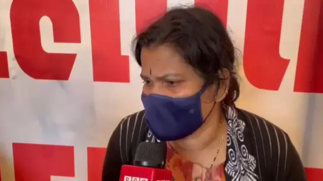 Devotee Sarojini wearing a mask speaks to the BBC via a microphone