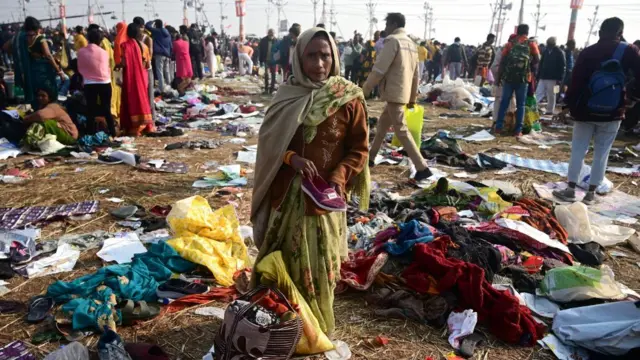 People stand among belongings of the victims following a stampede during the Kumbh Mela festival near Sangam Ghat in Prayagraj