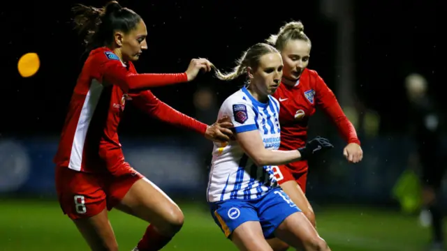 Bex Rayner of Brighton & Hove Albion is challenged by Mollie Lambert (L) and Carly Johns (R) of Durham during The Adobe Women's FA Cup Fourth Round match between Brighton & Hove Albion and Durham