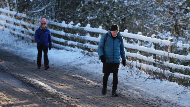 Two people walk through snow in Balerno, Edinburgh