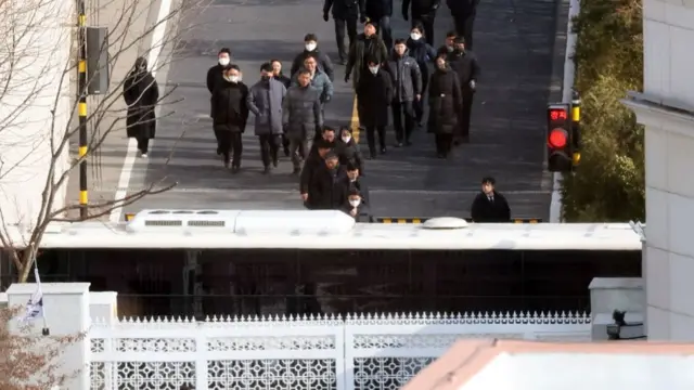 Investigators walking towards the gate of the presidential compound as they exit