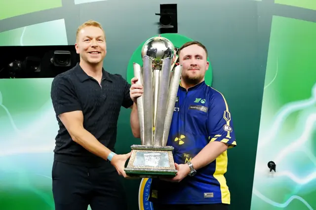 Sir Chris Hoy presents the World Championship trophy to Luke Littler