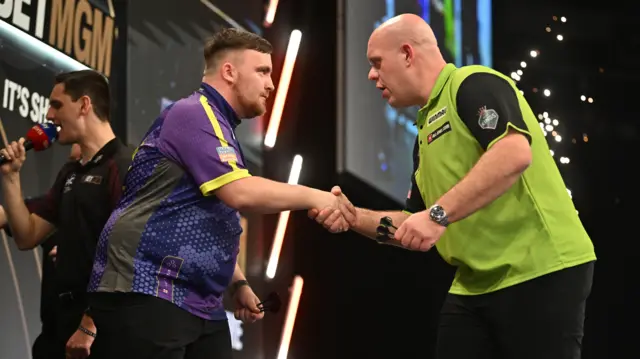 Luke Littler shakes hands with Michael van Gerwen