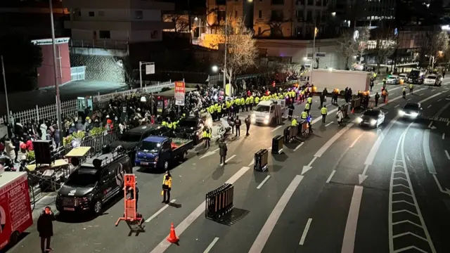 View of protesters crowding outside Yoon's residence in the dark