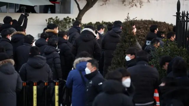 Back view of people in black winter coats entering Yoon's residence