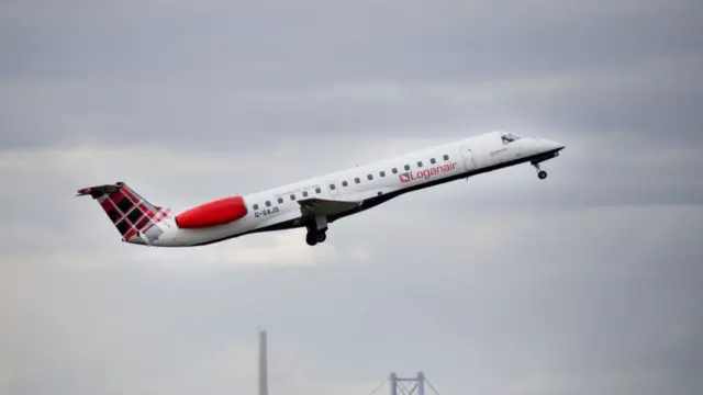 Loganair aircraft taking off. The tail of the plane is decorated in tartan with the left engine shell painted red. The top of a white bridge is visible to the bottom centre of the photo