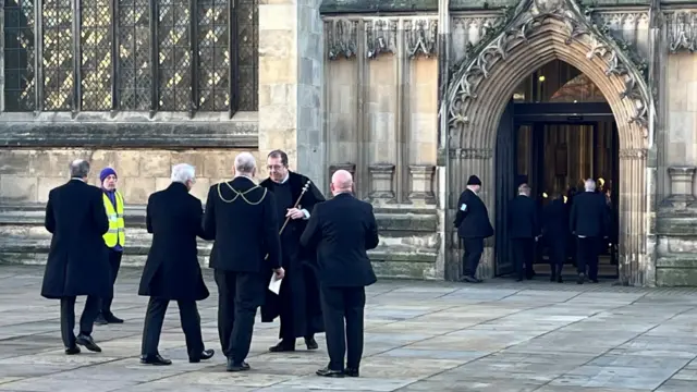 A reverend greets a group of three men outside Hull Minster