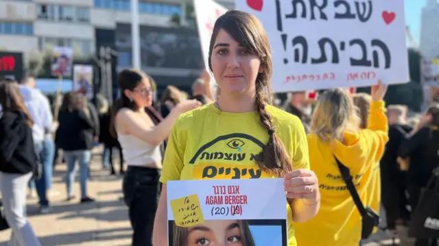 Woman in yellow t shire holding picture of Agam Berger