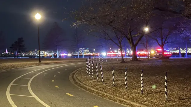 An empty road with emergency vehicle sirens further away near the Potomac River