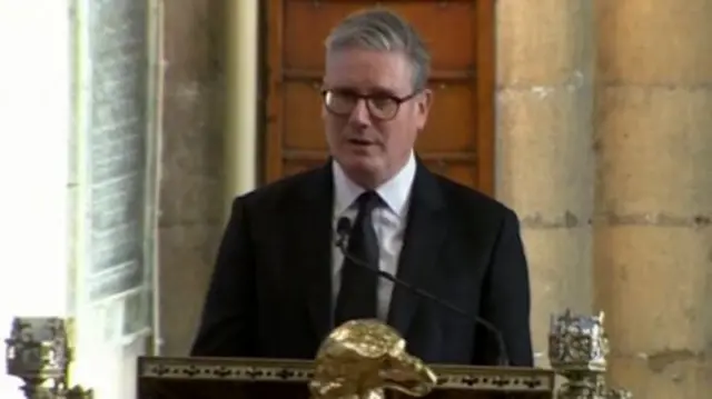 Keir Starmer in black suit, black tie and white shirt delivers reading