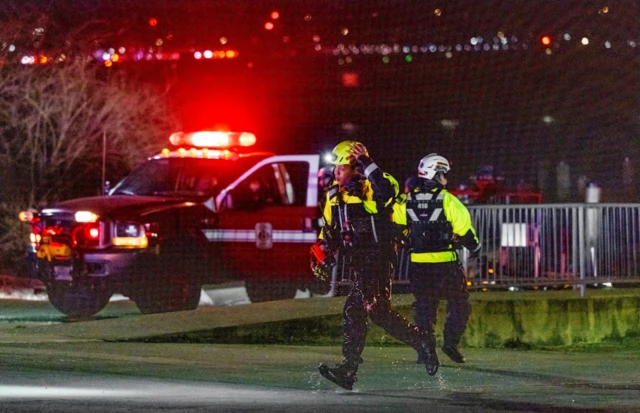 Rescue teams stage to help search the Potomac River after a commercial airplane reportedly collided with a military helicopter on approach to Ronald Reagan National Airport in Washington