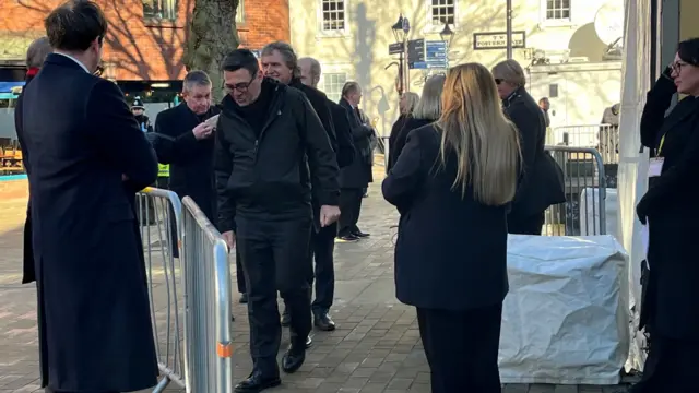 Burnham, wearing black, looks down as he walks past metal railings at the security checkpoint outside Hull Minster