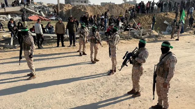 A row of militants holding guns and wearing camouflage.