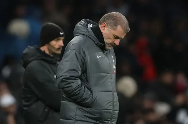 Ange Postecoglou stands with his head bowed on the sideline