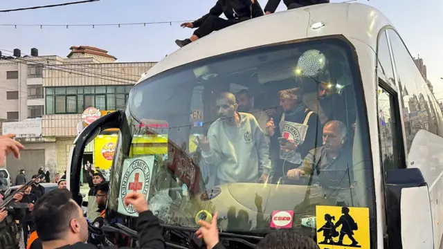 People surround and record a bus filled with passengers