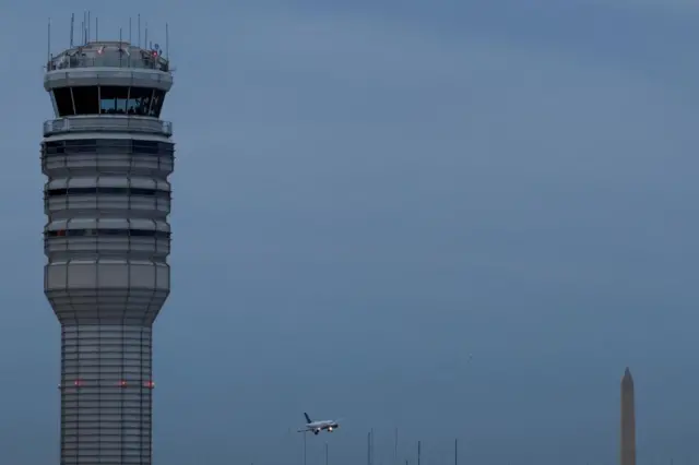 A plane flies next to an air traffic control near Ronald Reagan Washington National Airport