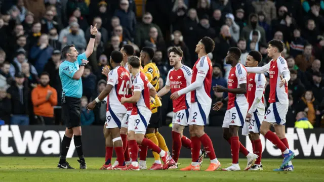 Arsenal players surround referee Michael Oliver