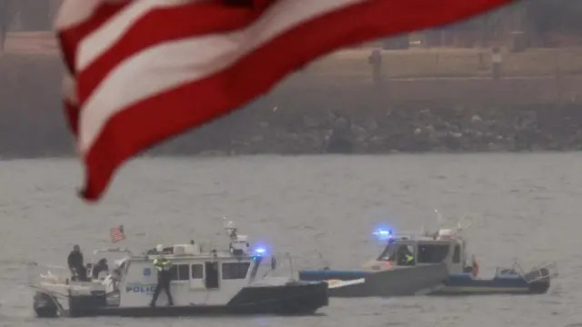 Search and rescue teams in the Potomac River. Part of the US flag can be seen in the foreground of the photo.