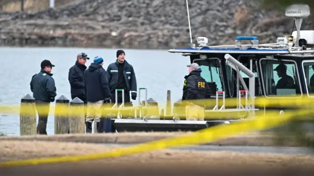 FBI officials gather on a boat; there's yellow caution tape in the foreground