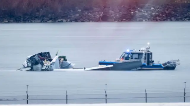 A police boa next to a wreckage in grey water