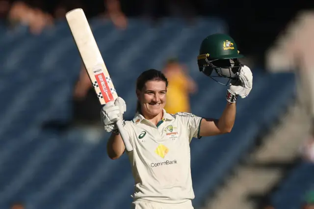 Annabel Sutherland raises her bat to salute her century