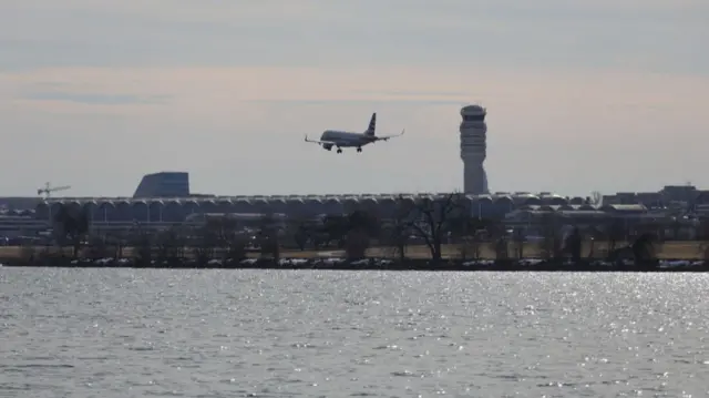 A plane flies low over water close to Reagan National Airport
