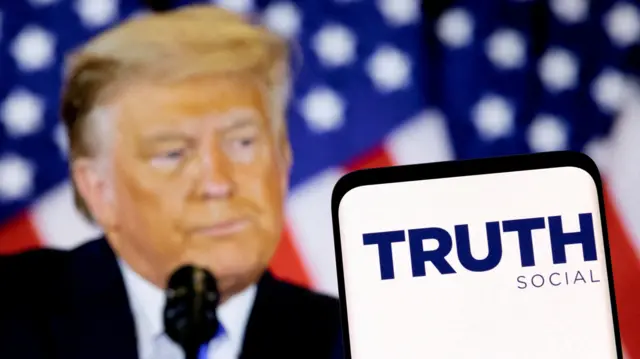 The Truth social network logo is seen on a smartphone in front of a display of US President Donald Trump in this picture illustration