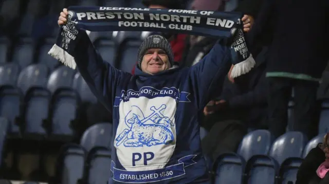 A Preston fan holding aloft his scarf