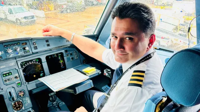 Mo Khimji sat in an airplanes's cockpit similing at the camera