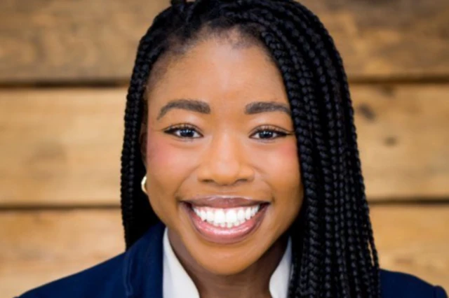 A professional headshot of Duggins, a young black woman, who smiles