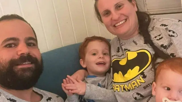 The family pose for a photo all smiling in their matching batman pyjamas