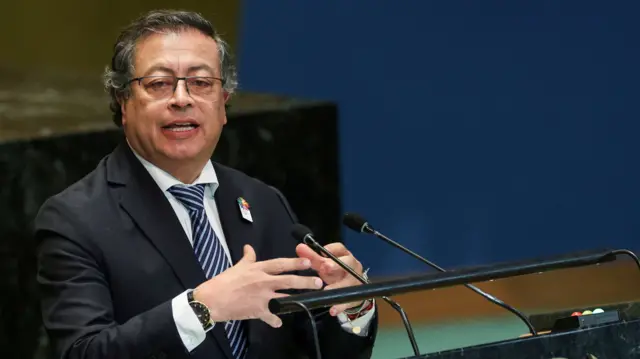 Gustavo Petro sits at a desk speaking into two microphones.