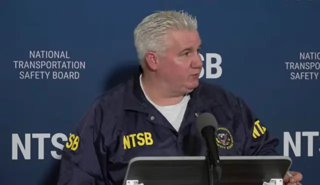 Inman appears before the press wearing a NTSB jacket