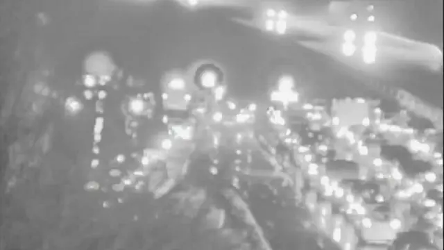 A blurry motorway camera image shows a long queue of car lights and some vehicles facing the wrong way.