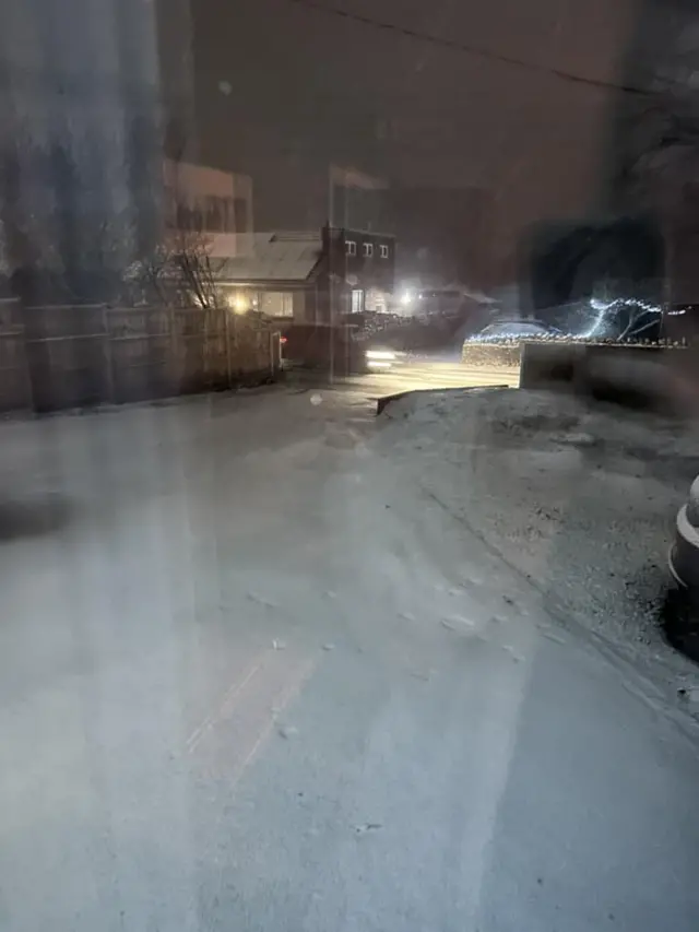 A residential road is covered in a layer of thick snow.