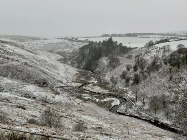 Hills and trees are covered in a light dusting of snow