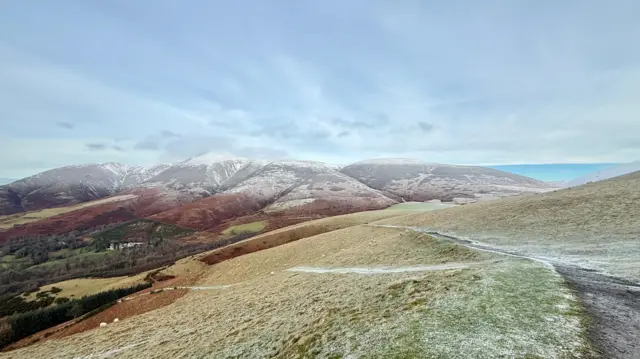 A view over Keswick hills with frost on the ground. The sea can be seen to the right